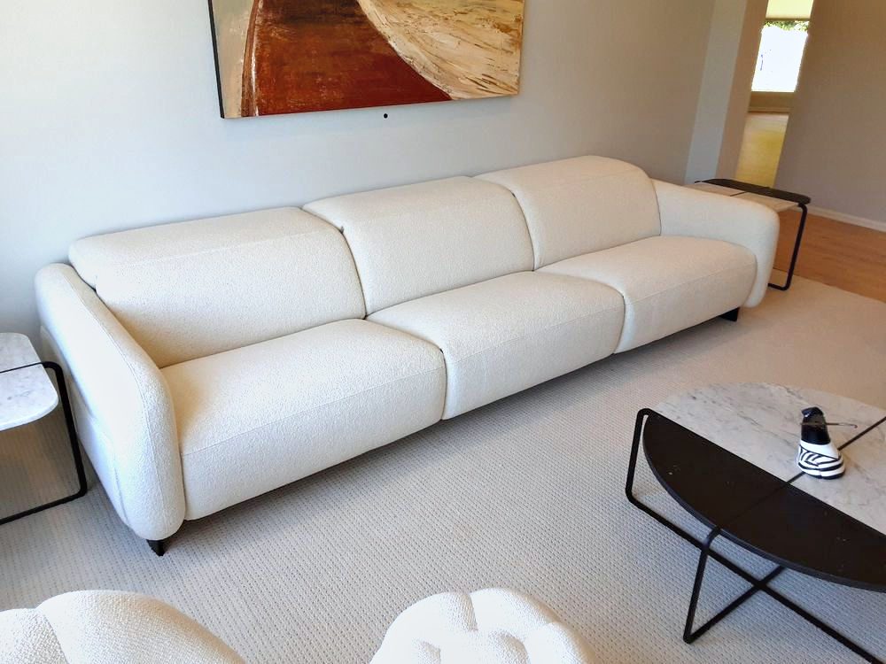 A long white sofa placed beneath artwork in a finished living room