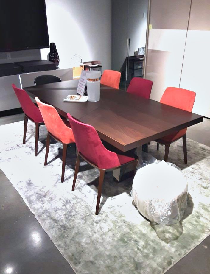 A dining table and chairs assembled and set on a rug during an installation